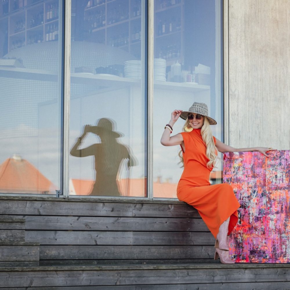 holder på hat og smiler i orange kjole – stor-kopi